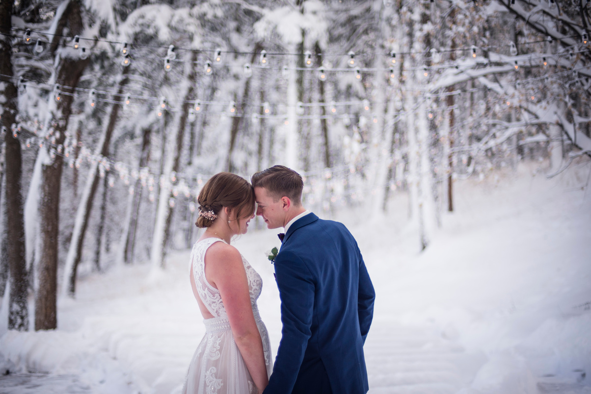 A bride and groom embrace in the snow at their winter wedding at The Pines at Genesee in Genesee, Colorado.
