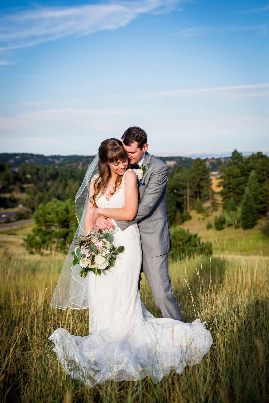 A romantic shot of a groom snuggling his bride from behind at The Pines at Genesee wedding venue in Denver, Colorado.