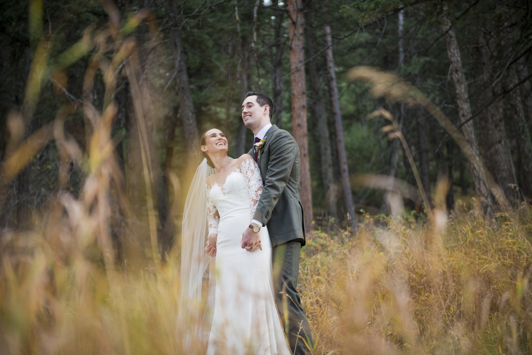 A bride and groom playfully look at each other in a golden field at The Pines at Genesee in Genesee, Colorado.