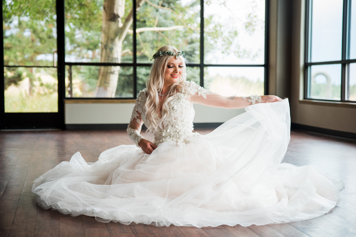 A whimsical bride sitting on the floor in her wedding dress at The Pines at Genesee in Denver, Colorado.