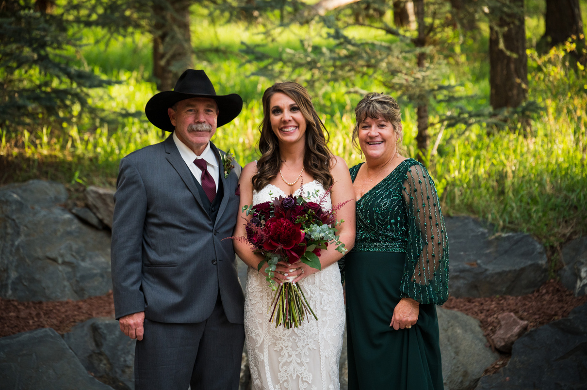 A bride poses for a photo with her parents.