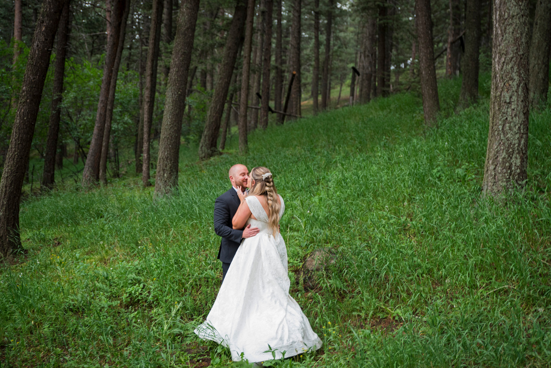 A bride and groom embracing and smiling at each other in the Evergreen Forest at The Pines at Genesee.