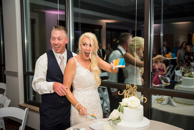 A bride and groom with surprised faces cutting their wedding cake, captured by Denver wedding photographer Casey Van Horn.