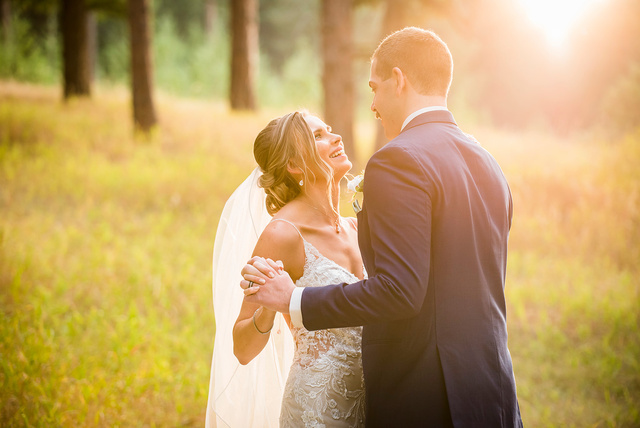 A bride and groom embrace in a field at sunset at The Pines at Genesee.