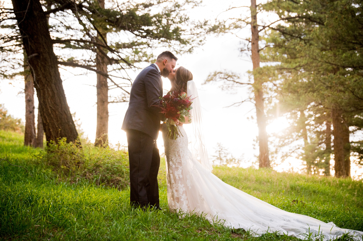 A bride and groom sharing a kiss at sunset at The Pines at Genesee in Denver, Colorado.